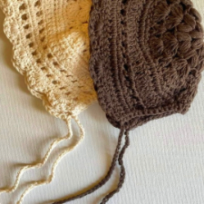 Crocheted bonnet with strings and scalloped edge.