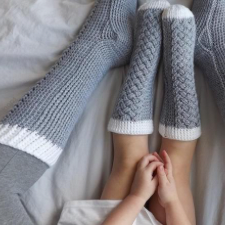 Knee-high socks on an adult and a small child. Intricate cable runs the full length of the top of the sock.