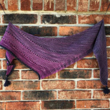 Shallow boomerang shawl, mostly garter stitch with some yarnovers. Tassel at each end of the horizontal edge, then a border with contrasting yarn woven through purl rows for an interesting effect.