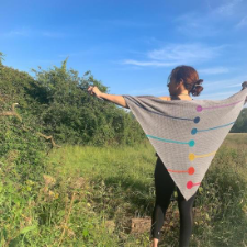 Single crochet triangular shawl with colorful circles down the spine. Circles have horizontal lines alternating left and right toward the shawl’s edges.