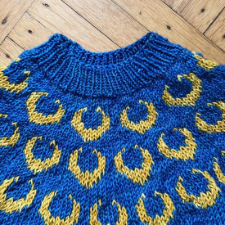 Knitted colorwork sweater with three rows of crescent moons at the yoke.