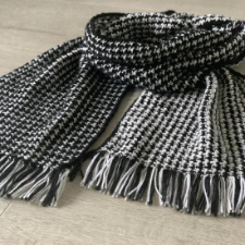 Rectangular scarf with fringe in high-contrast houndstooth pattern.