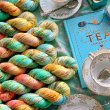 Soft, warm variegated skeins, reminiscent of flower gardens, shown with cups of tea and a Downton Abbey book.