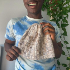 Smiling designer holding crocheted beanie