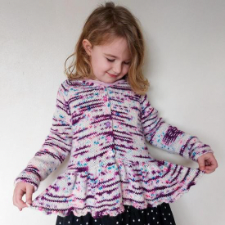 Child in a long-sleeve cardigan with a long ruffle at the hem.