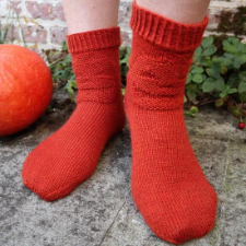 Socks with a jack-o’-lantern in purl stitches across the front of the calf.