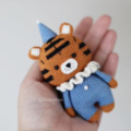 Crocheted tiger in simple clown costume with pointy hat, ruffed collar and a button on the front.