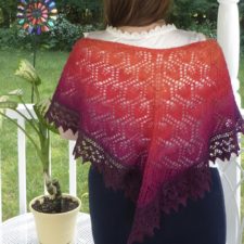 Triangular lace shawl knitted in gradient yarn.