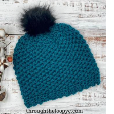 Textured crocheted beanie with faux fur poof and scalloped brim.