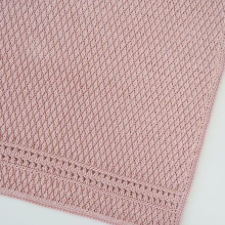 Blanket in diamond-shaped stitches with openwork stripe near the bottom.