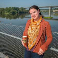 Woman in blazer. Underneath is a cowl-neck shawl with a long, bandana style front.