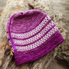 Beanie with contrasting criss-cross weaving in three bands through some of the purl stitches.