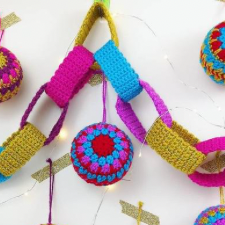 Crocheted chain in bright colors and metallic gold, made to look like a paper garland. Multicolored crochet ornaments, too.