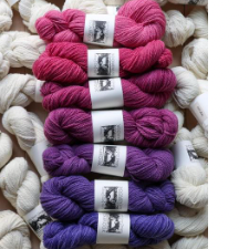 Stack of skeins in gradient from medium pink to medium purple.