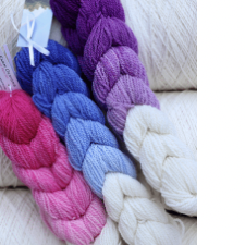 Braids of yarn in a gradient from bright white to deep pink, blue or purple.