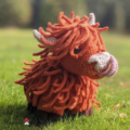 Adorable red, long “haired” cow with horns. Cow is licking its own nose with long pink tongue.