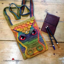 Flat bag with dragon’s face and scales, along with shoulder strap. created in multicolor yarn.
