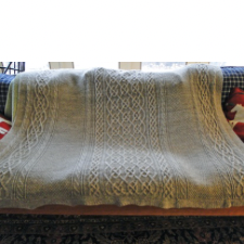Sofa blanket with ornate vertical cabled sections.