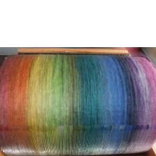 Carding drum with a rainbow of fiber wrapped around it.