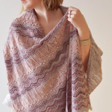 Asymmetrical shawl worked sideways from tip with irregular side increases along its left edge. Shawl features three pattern panels with softly transitioning scalloped lace and light textures.