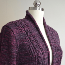 Elegant cardigan with panels of cables and braids features flattering high collar.