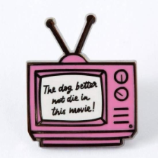 Enamel pin of a pink vintage TV with the words “The dog better not die in this movie!” on the screen