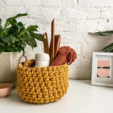 Large crocheted rope basket with leather handles, full of weaving tools.