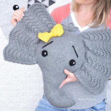 Knitted cartoon-style elephant head with a bow next to one of the wavy lace ears.