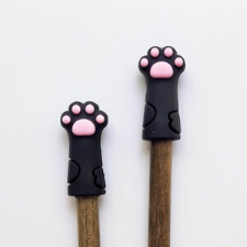 Black cat paws with pink toe pads sit atop two needles.