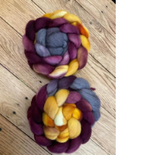 Two coiled braids of fiber in deep maroon, gold and dusty purple.
