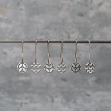 Six round metal markers on bulb pins. Three markers are engraved with garter stitch, and three are engraved with stockinette.