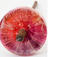 Drop spindle with a colorful resin whorl in warm shades.