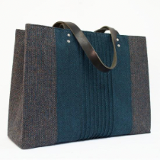 Rectangular tote in neutral color has deep aqua pleated center section. Handles are leather and bag also has a strong magnetic closure.