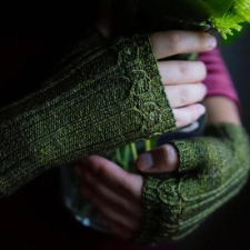 These fingerless gloves offer a touch of decorative warmth with their twisted stitch and bobble motif.