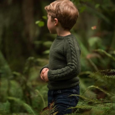 Child’s crewneck pullover with a cable down the outside of the long sleeve.