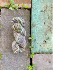 Handspun Aran yarn reflects soft colors in garden tiles around it.