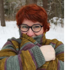 Woman with twinkling eyes bundles up in roomy striped cardigan.