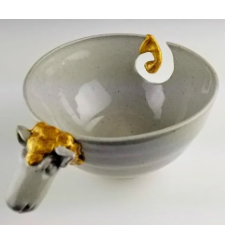 Yarn bowl with sheep head at one end and tail in the swirl that manages the yarn at the other. Sheep’s head curls and tail are overlaid with gold.