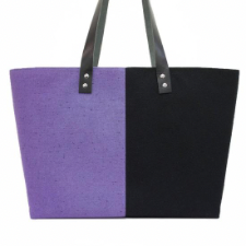 Two-color tote, divided vertically, with leather handles. Colors are deepest black and lilac. Tote