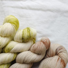 Hand-dyed, variegated skeins in warm pale greens and browns.