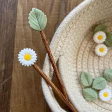 Daisy and leaf shaped needle stops in soft colors.