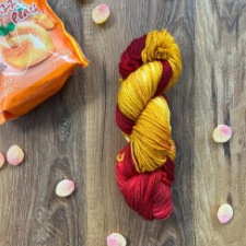 Two-color variegated yarn shown with similarly hued peach jelly candies.
