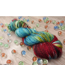 Red and blue variegated yarn with hints of yellow. Yarn is shown with scattered matching swirl marbles.