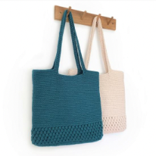 Two totes hang on pegboard. Totes have crocheted shoulder handles, then a solid crocheted fabric in two stitches. The first runs from the bottom hem up about the length of a finger. Second covers the rest of the bag.