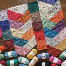 Modular blanket made with columns of stacked half-hexagons, turned to look like a braid, alternated with columns of crocheted squares.