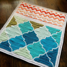Baby blanket with Moroccan tile shapes and a band of chevrons at the top.