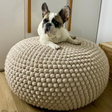 French bulldog lying atop large bobbled pouf.