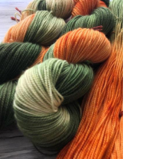 Variegated yarn in greens, along with a pumpkin orange.