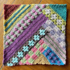 Blanket square in stacking diagonal strips that contain numerous colors and textures.