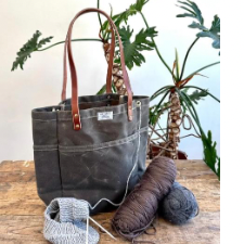 Tote bag with leather handles. Has grommet-style opening for yarn.